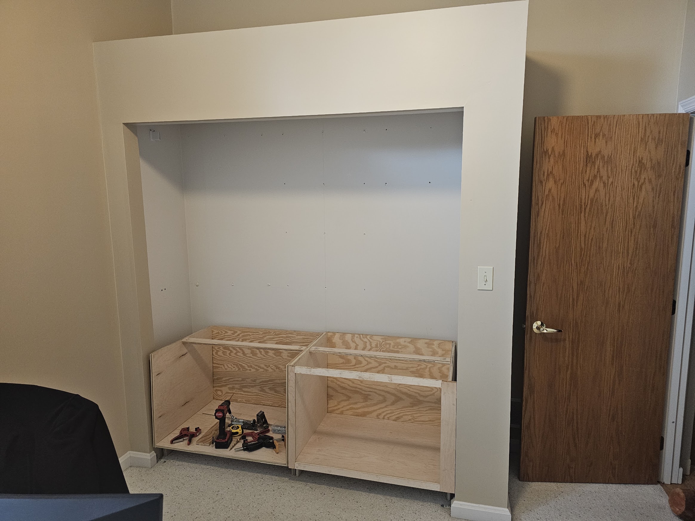 Two plywood cabinet carcasses under construction inside the closet opening
