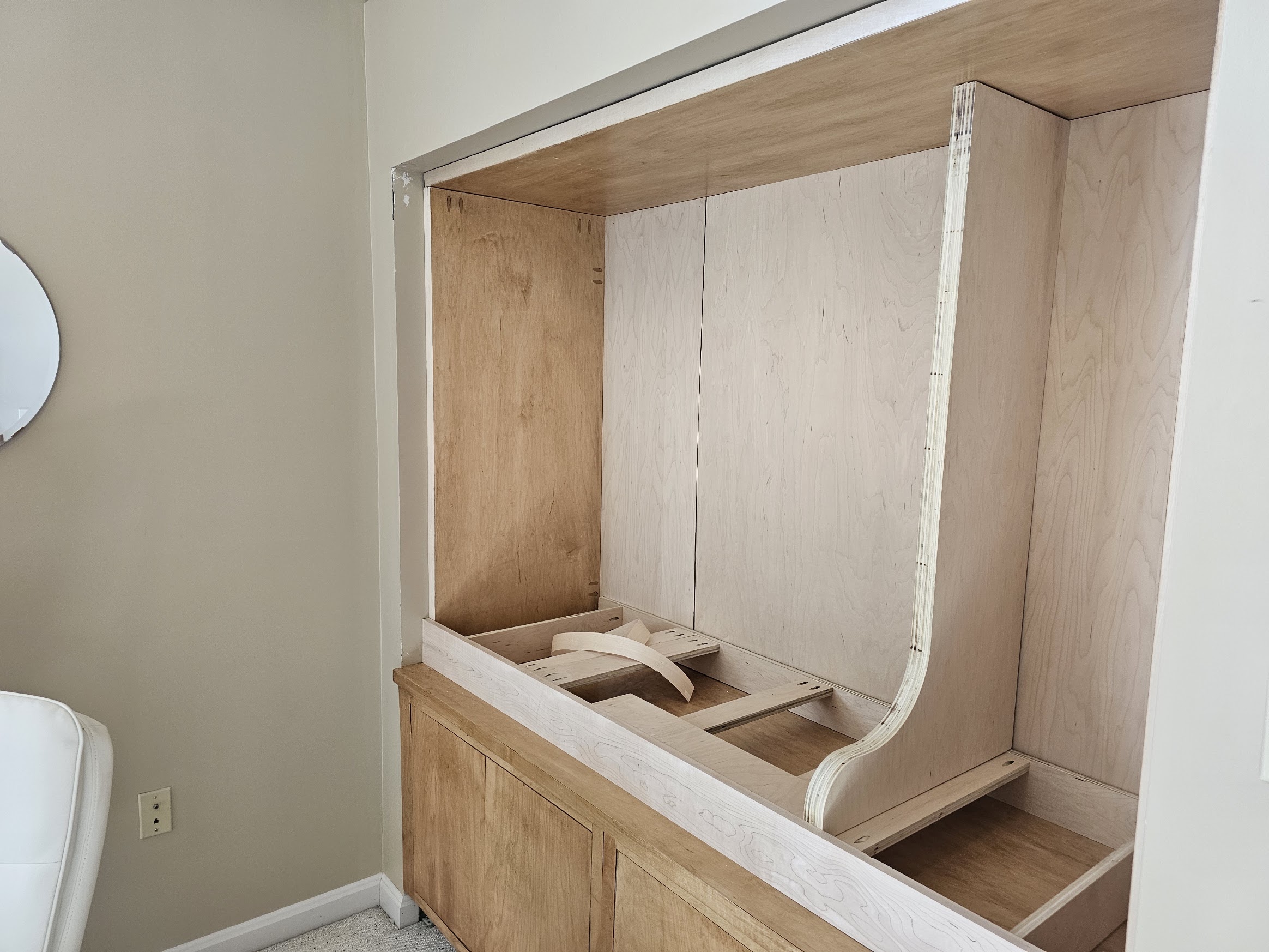 Plywood vertical divider with a long curved profile installed inside the built-in